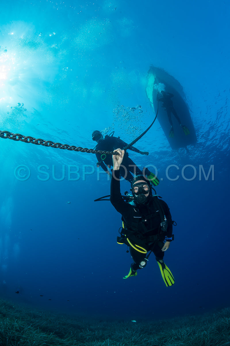 Photo de Plongeurs effectuant un palier de décompression sous leur bateau de plongée